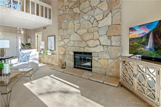 living room with visible vents, a stone fireplace, carpet flooring, and a high ceiling