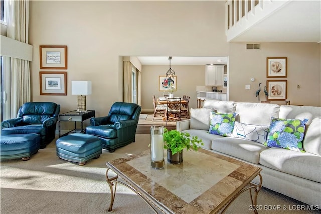 carpeted living room with visible vents and a towering ceiling