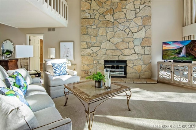 carpeted living area featuring a stone fireplace and visible vents