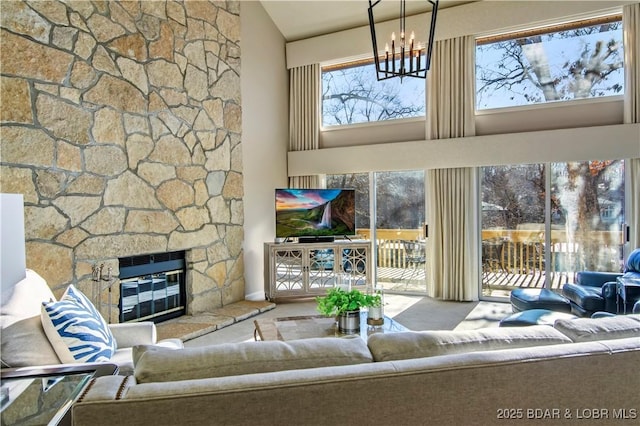 unfurnished living room featuring a chandelier, high vaulted ceiling, a stone fireplace, and carpet floors