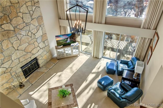 living room featuring heating unit, a high ceiling, carpet floors, a fireplace, and a chandelier