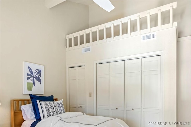 bedroom featuring two closets, a towering ceiling, and visible vents