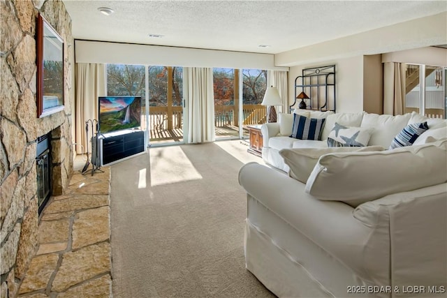 carpeted living room with a textured ceiling, a fireplace, and visible vents