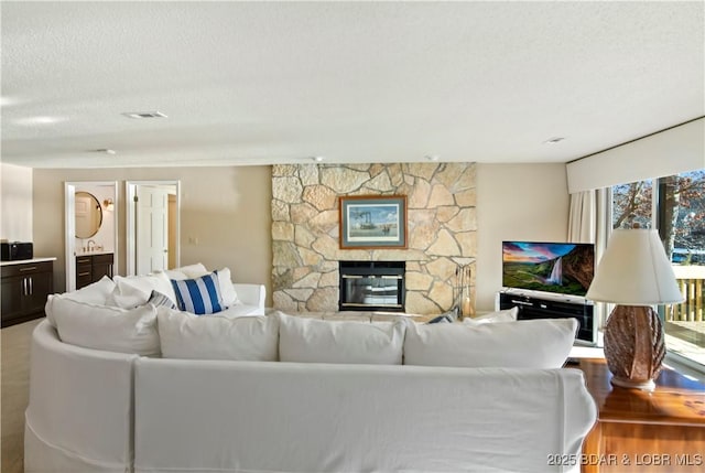 living room featuring a textured ceiling, a fireplace, wood finished floors, and visible vents