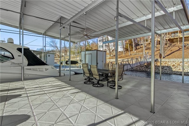 view of patio featuring a storage unit, outdoor dining area, and an outbuilding