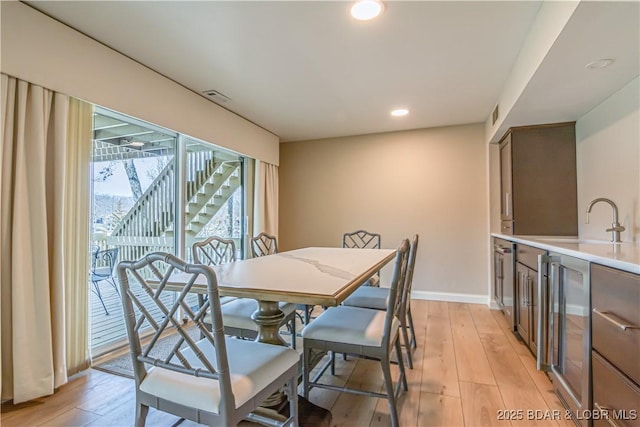 dining space with wine cooler, visible vents, light wood-style flooring, and baseboards