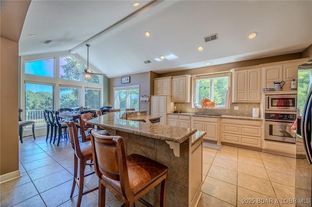 kitchen featuring a breakfast bar area, a sink, visible vents, appliances with stainless steel finishes, and decorative backsplash