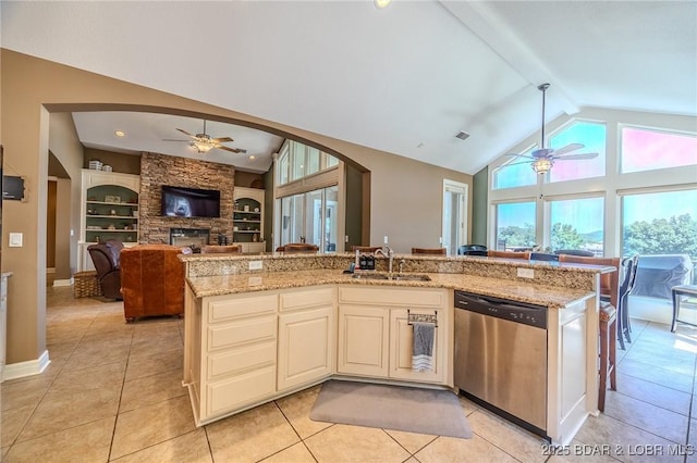 kitchen with open floor plan, stainless steel dishwasher, a sink, and light stone counters