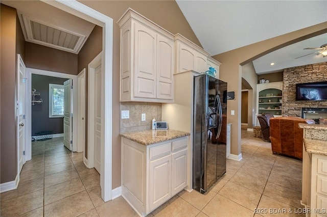 kitchen with open floor plan, light tile patterned floors, arched walkways, and black fridge with ice dispenser