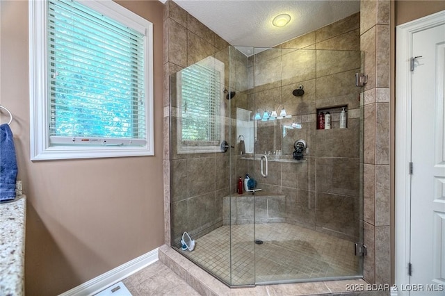 full bathroom featuring a stall shower, tile patterned flooring, baseboards, and a textured ceiling