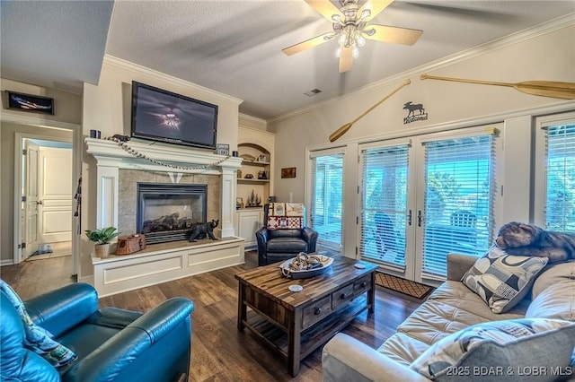 living room featuring a fireplace, crown molding, a textured ceiling, and wood finished floors