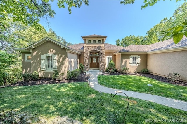 mediterranean / spanish-style house with stone siding, french doors, a front lawn, and stucco siding