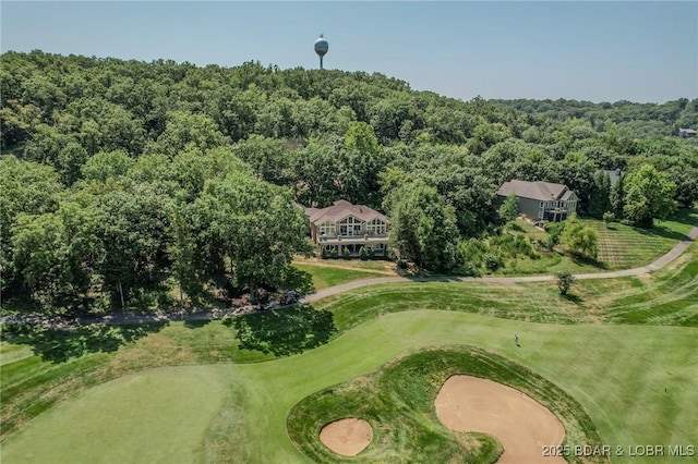 drone / aerial view featuring golf course view and a wooded view