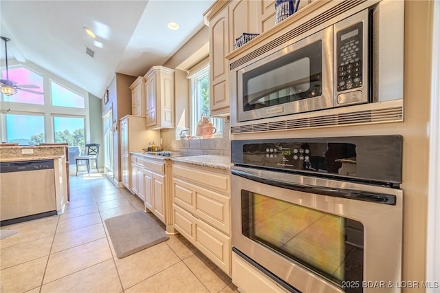 kitchen with lofted ceiling, light tile patterned floors, stainless steel appliances, and a wealth of natural light