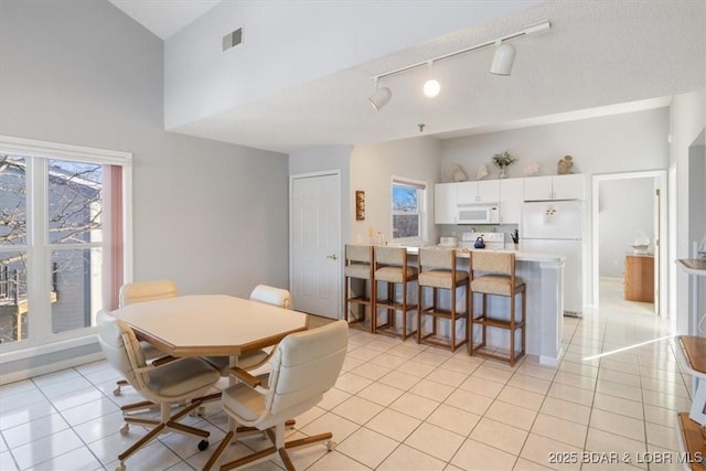 dining room featuring light tile patterned floors, a towering ceiling, visible vents, and plenty of natural light