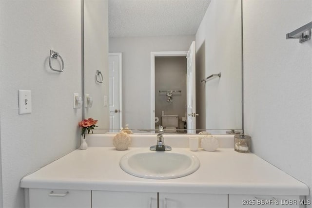 bathroom featuring a textured ceiling, vanity, and toilet