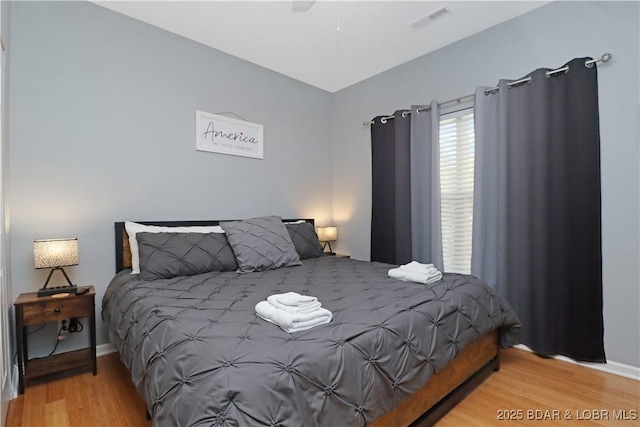 bedroom featuring baseboards, wood finished floors, visible vents, and a ceiling fan