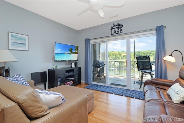 living room with visible vents, wood finished floors, and a ceiling fan