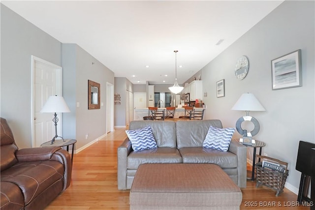 living area featuring light wood-type flooring, baseboards, and recessed lighting