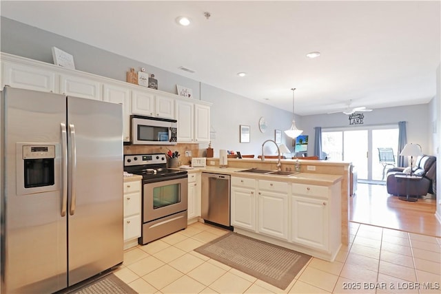 kitchen featuring stainless steel appliances, open floor plan, light tile patterned flooring, a sink, and a peninsula