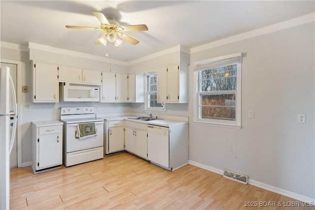 kitchen with white appliances, a sink, visible vents, light countertops, and light wood finished floors