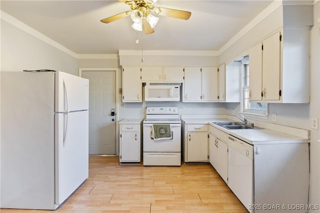 kitchen with crown molding, light countertops, light wood-style flooring, a sink, and white appliances