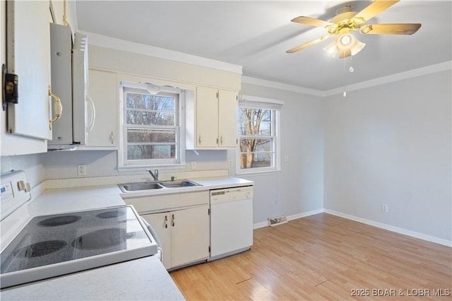 kitchen with light countertops, visible vents, ornamental molding, a sink, and white appliances