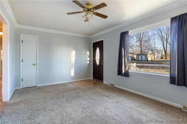 carpeted entrance foyer with ornamental molding, a healthy amount of sunlight, visible vents, and baseboards