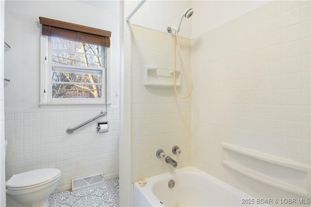 bathroom featuring visible vents, toilet, a wainscoted wall, bathtub / shower combination, and tile walls