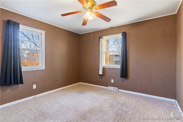 spare room with baseboards, carpet, visible vents, and a wealth of natural light