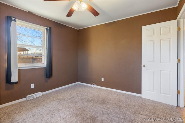 empty room featuring baseboards, visible vents, crown molding, and carpet flooring