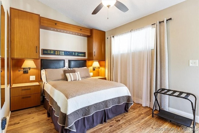 bedroom featuring light wood-type flooring, lofted ceiling, and a ceiling fan