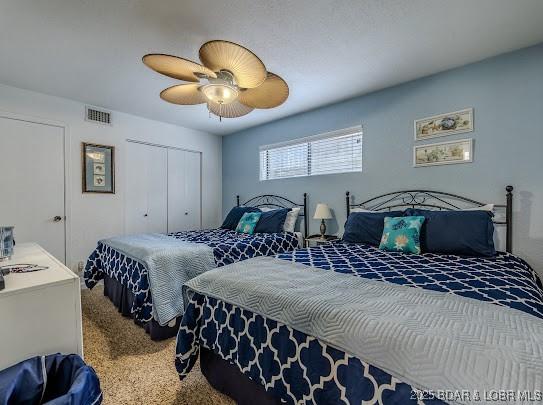 bedroom with a ceiling fan, visible vents, a closet, and carpet flooring