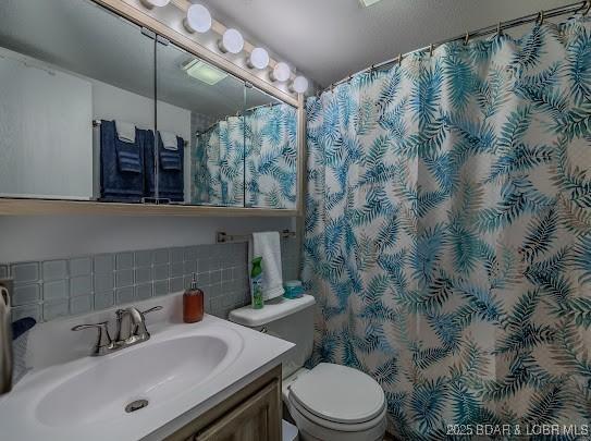 full bathroom with decorative backsplash, curtained shower, vanity, and toilet