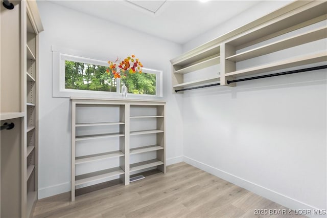 walk in closet with light wood-style floors