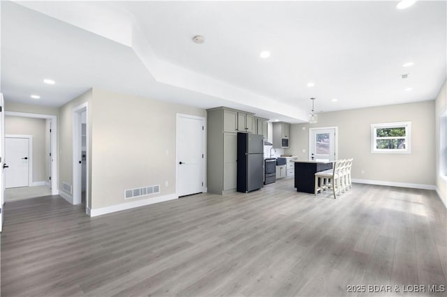 kitchen with gray cabinets, light countertops, visible vents, freestanding refrigerator, and a kitchen island