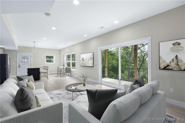 living room with light wood-style floors, visible vents, baseboards, and recessed lighting