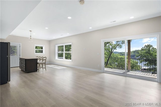 interior space with a breakfast bar area, light wood finished floors, recessed lighting, freestanding refrigerator, and baseboards