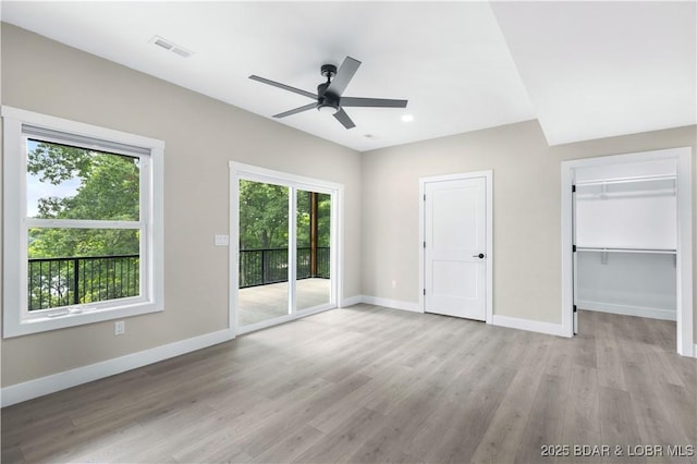 unfurnished bedroom with light wood finished floors, visible vents, a spacious closet, access to outside, and baseboards