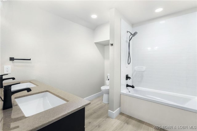 full bathroom featuring toilet, wood finished floors, a sink, shower / washtub combination, and double vanity