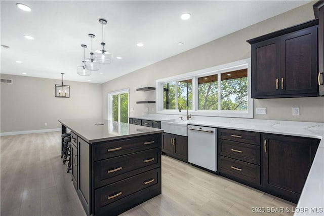 kitchen with pendant lighting, recessed lighting, white dishwasher, a sink, and light wood-type flooring