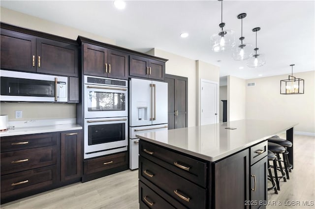 kitchen with light wood-type flooring, white appliances, light countertops, and decorative light fixtures