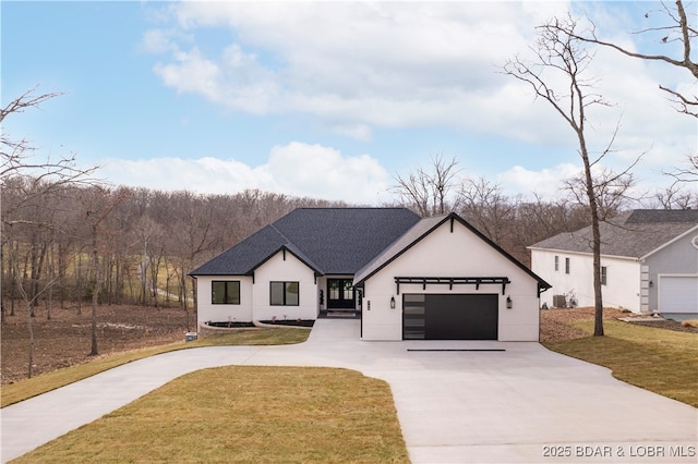 modern inspired farmhouse with stucco siding, an attached garage, concrete driveway, and a front yard