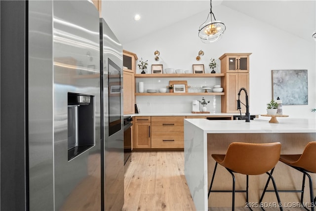 kitchen with open shelves, light countertops, vaulted ceiling, stainless steel refrigerator with ice dispenser, and a kitchen breakfast bar