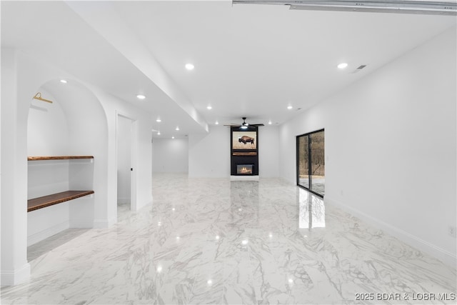 unfurnished living room featuring ceiling fan, marble finish floor, a glass covered fireplace, and recessed lighting