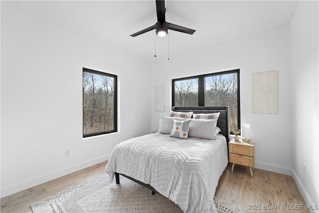 bedroom with multiple windows, a ceiling fan, light wood-type flooring, and baseboards