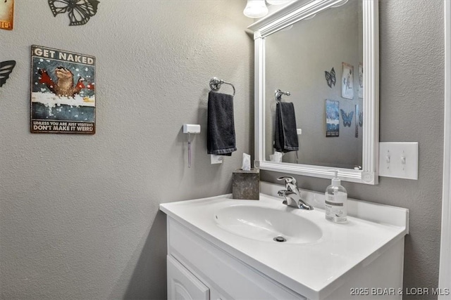 bathroom featuring a textured wall and vanity