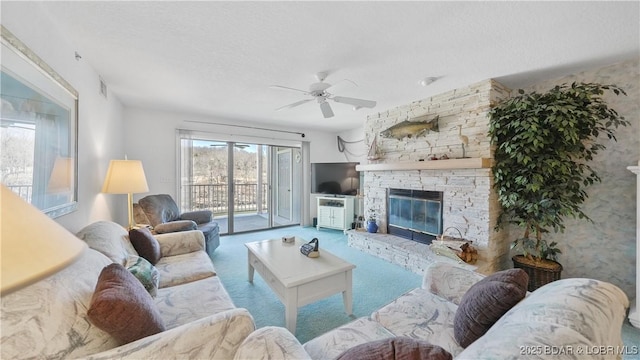 carpeted living room featuring ceiling fan, a stone fireplace, a textured ceiling, and visible vents