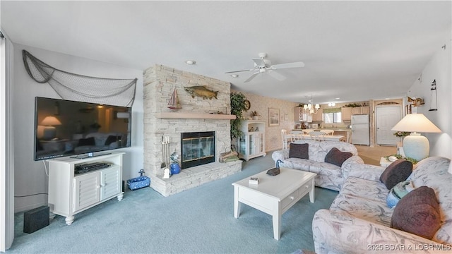 living room with light carpet, a fireplace, and ceiling fan with notable chandelier