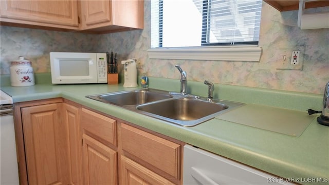 kitchen with white appliances, light countertops, and a sink